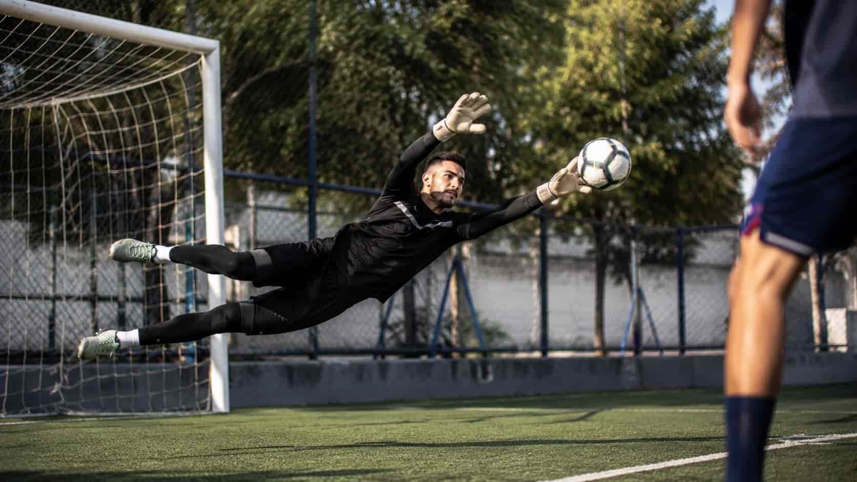Goleiro amador fazendo uma defesa
